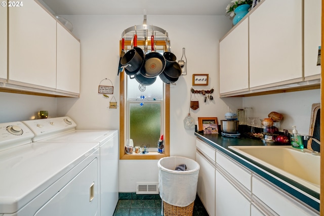 clothes washing area with separate washer and dryer, cabinets, sink, and dark tile patterned floors