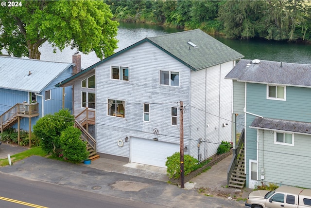 back of property with a garage and a water view