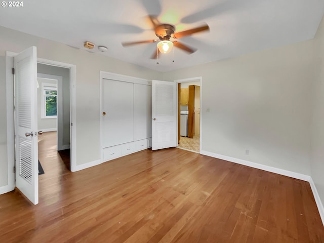 unfurnished bedroom featuring a closet, washer / clothes dryer, ceiling fan, and hardwood / wood-style floors