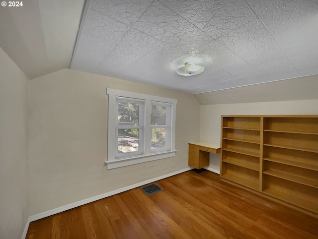 additional living space featuring lofted ceiling and hardwood / wood-style flooring