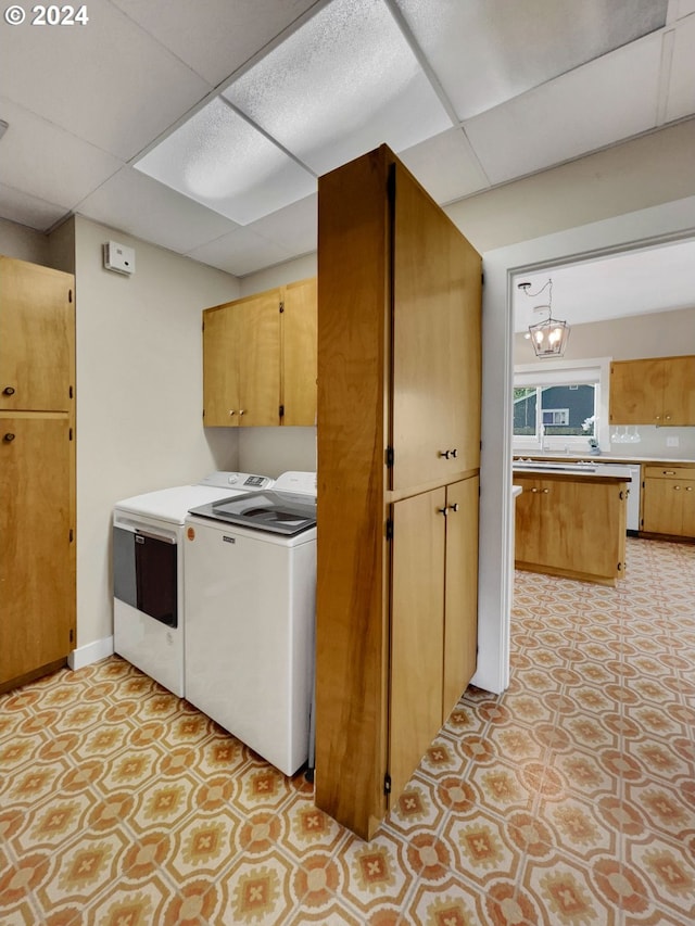 washroom with washer and clothes dryer, cabinets, and an inviting chandelier