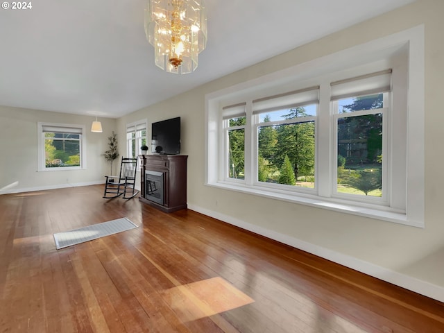 unfurnished living room with a chandelier and hardwood / wood-style floors