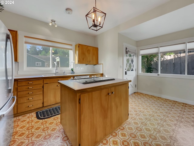 kitchen with stainless steel refrigerator, a kitchen island, pendant lighting, and plenty of natural light