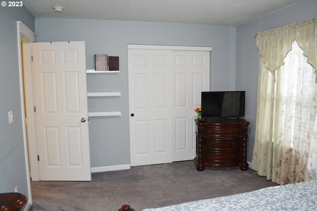 bedroom featuring dark carpet, a closet, and a textured ceiling