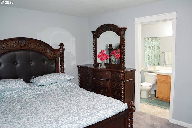 bedroom with light colored carpet, a textured ceiling, and connected bathroom