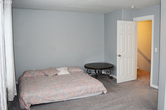 bedroom featuring carpet floors, baseboards, and a textured ceiling