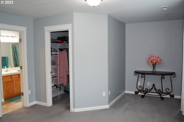 bedroom featuring carpet floors, a textured ceiling, connected bathroom, and sink