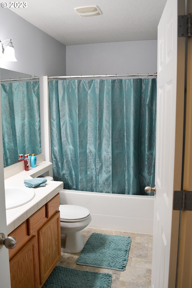 full bathroom featuring shower / bath combo with shower curtain, vanity, toilet, and stone finish flooring