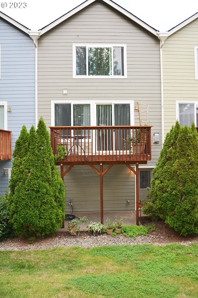 back of property featuring a deck and a lawn