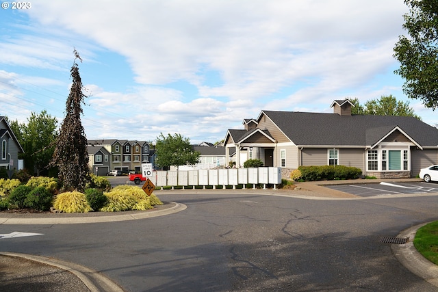 view of asphalt street with a residential view, traffic signs, and curbs