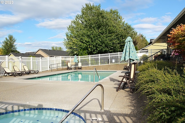 community pool with a patio, fence, and a community hot tub