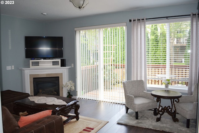 living room with hardwood / wood-style flooring, a tiled fireplace, and a wealth of natural light