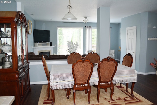 dining room with wood finished floors, baseboards, and a fireplace