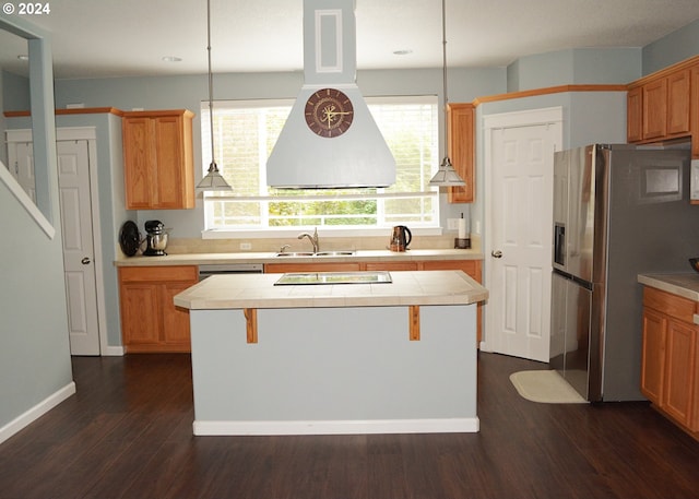 kitchen with hanging light fixtures, dark wood-type flooring, stainless steel appliances, tile countertops, and a center island