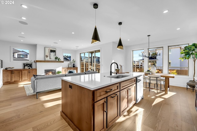 kitchen featuring a kitchen island with sink, sink, decorative light fixtures, light hardwood / wood-style flooring, and a notable chandelier