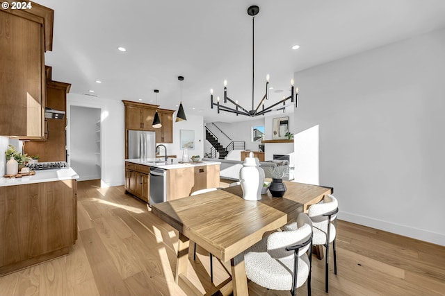 dining area featuring an inviting chandelier, sink, and light hardwood / wood-style flooring