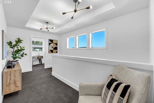 living area featuring a tray ceiling, a chandelier, and dark carpet