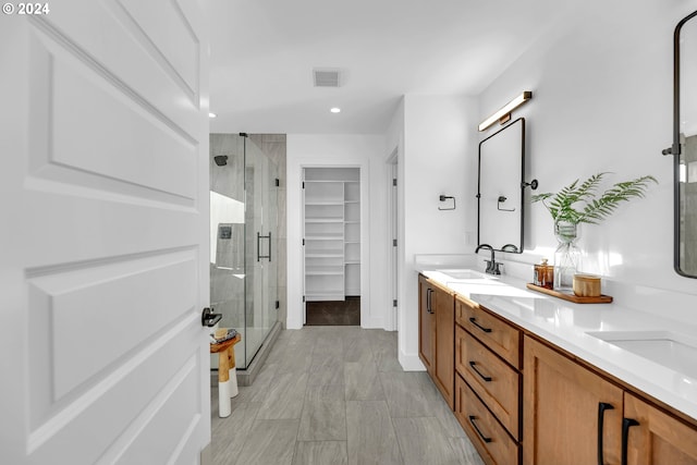 bathroom featuring a shower with door and vanity