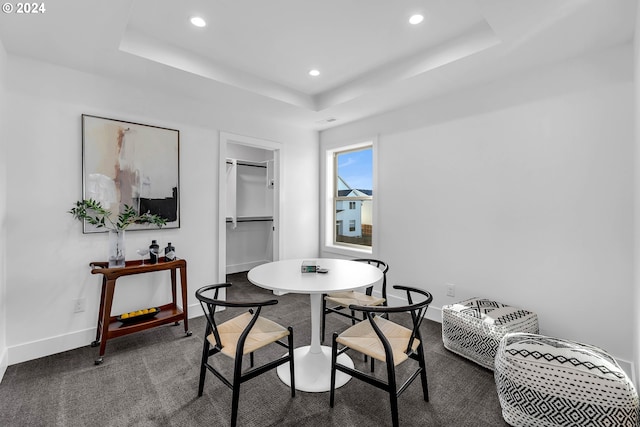 dining room with dark carpet and a raised ceiling