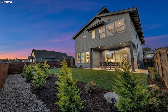 back house at dusk with a yard and a patio