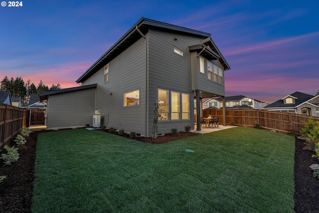 back house at dusk featuring a lawn, a patio, and central AC unit