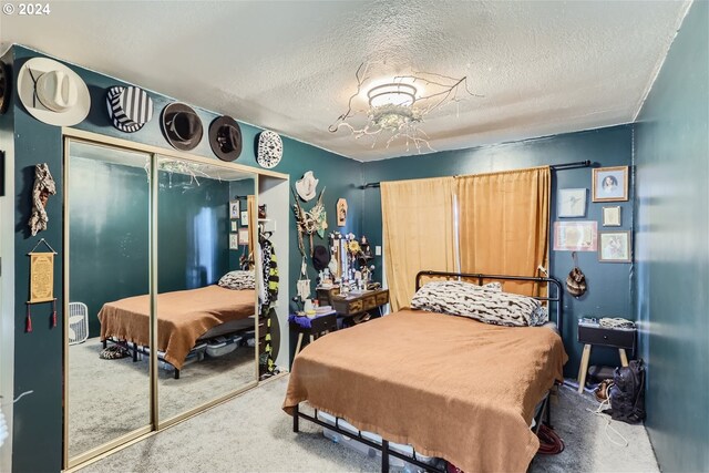 carpeted bedroom with a textured ceiling and a closet