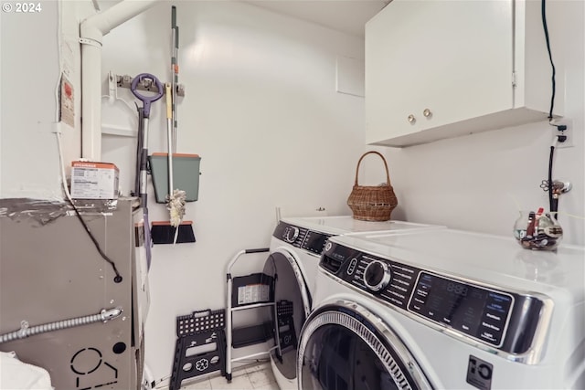 laundry area with washing machine and clothes dryer, light tile patterned flooring, and cabinets