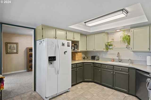 kitchen featuring green cabinets, a sink, white refrigerator with ice dispenser, stainless steel dishwasher, and a raised ceiling