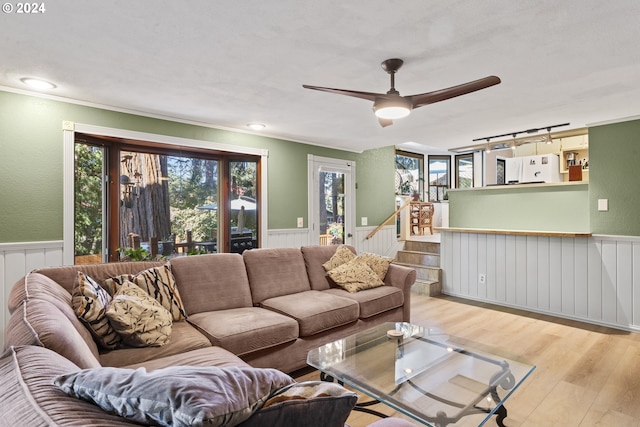 living area featuring track lighting, ceiling fan, stairs, wainscoting, and wood finished floors