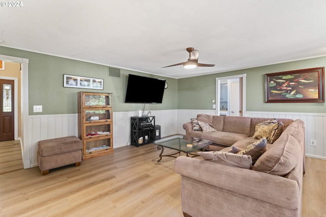 living room featuring light wood-type flooring, visible vents, and wainscoting