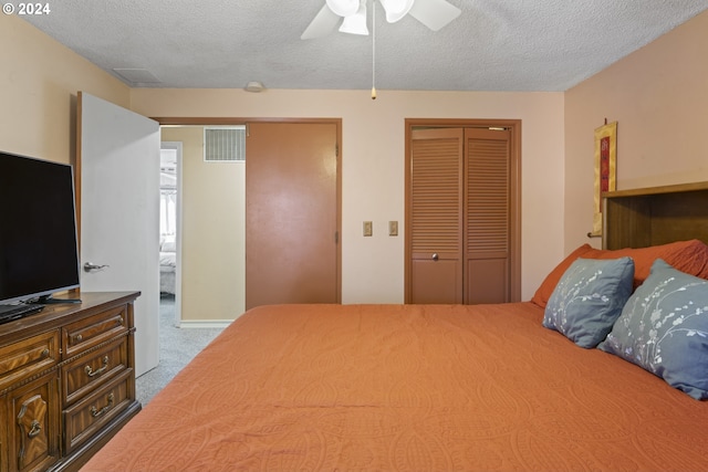 carpeted bedroom featuring visible vents, multiple closets, a textured ceiling, and a ceiling fan