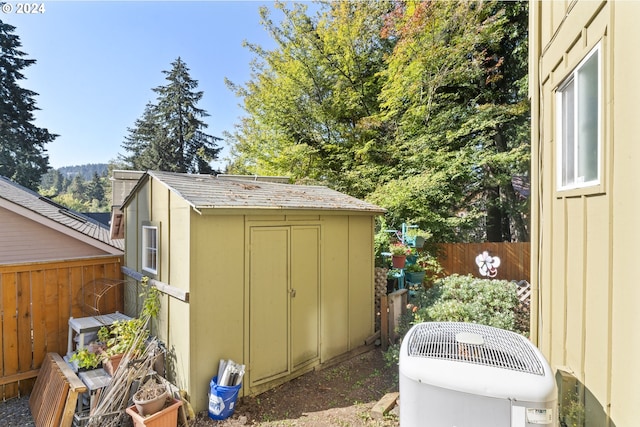 view of shed with cooling unit and fence