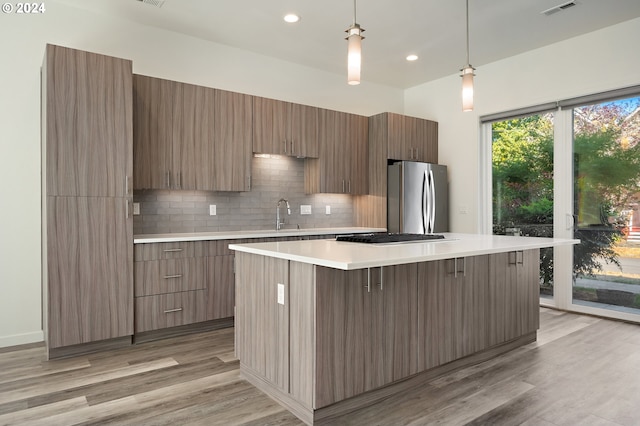 kitchen with modern cabinets, a kitchen island, light countertops, and freestanding refrigerator