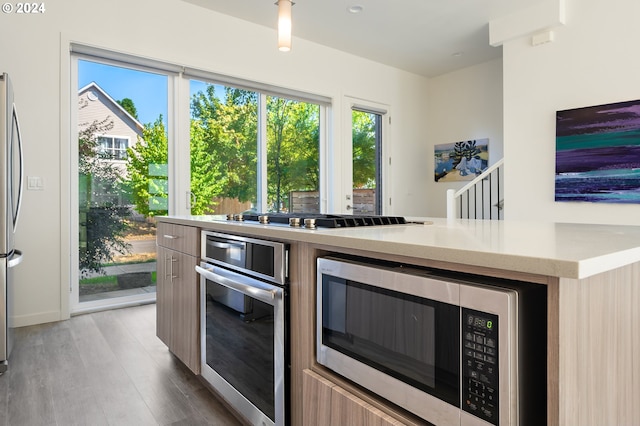 kitchen featuring appliances with stainless steel finishes, light countertops, and wood finished floors