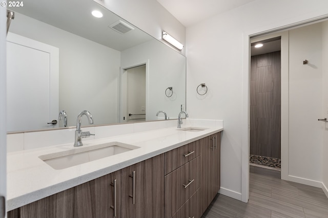 bathroom with tile patterned flooring, vanity, and a tile shower