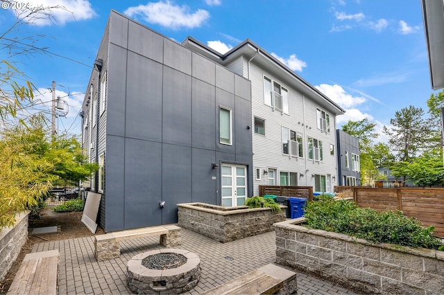 back of property featuring an outdoor fire pit, fence, and a patio