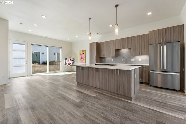 kitchen with light countertops, freestanding refrigerator, a center island, brown cabinetry, and decorative light fixtures