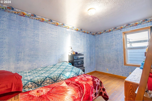 bedroom with hardwood / wood-style floors and a textured ceiling