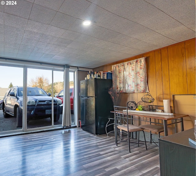 kitchen featuring black refrigerator, hardwood / wood-style floors, and wood walls