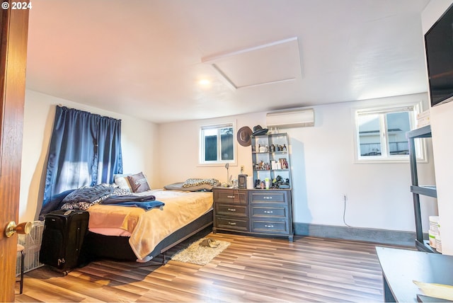 bedroom with an AC wall unit and light hardwood / wood-style floors