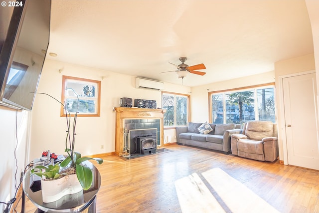 living room with ceiling fan, light wood-type flooring, a wood stove, and an AC wall unit