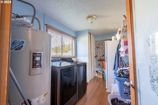 laundry area featuring wood-type flooring, electric water heater, a textured ceiling, and washer and clothes dryer