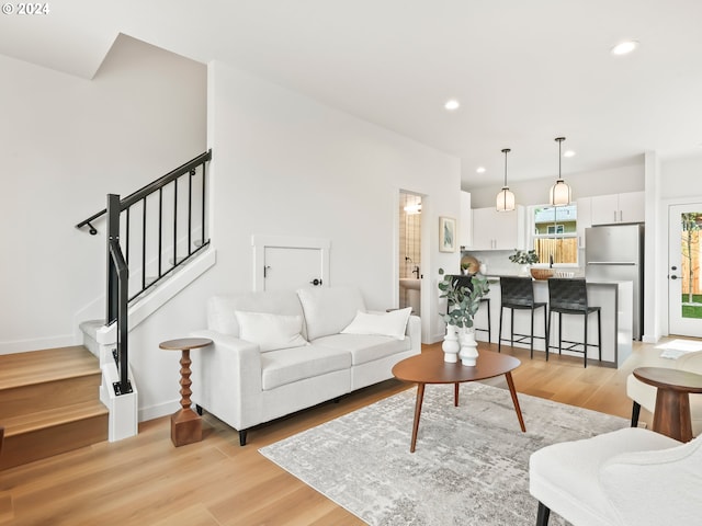 living room featuring light wood-type flooring, stairs, baseboards, and recessed lighting