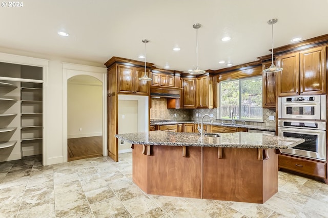 kitchen with pendant lighting, backsplash, a center island, and dark stone counters