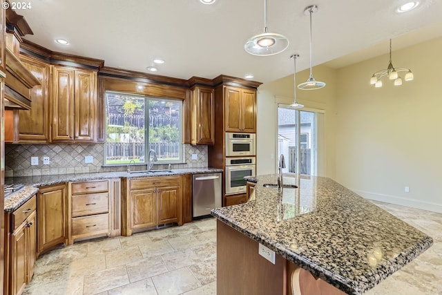 kitchen featuring appliances with stainless steel finishes, backsplash, sink, decorative light fixtures, and an island with sink