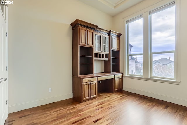 unfurnished office featuring light wood-type flooring and built in desk