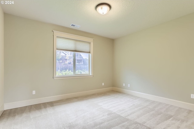 empty room with a textured ceiling and light colored carpet