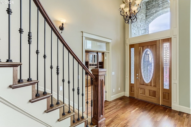 foyer entrance featuring a high ceiling, hardwood / wood-style flooring, and an inviting chandelier