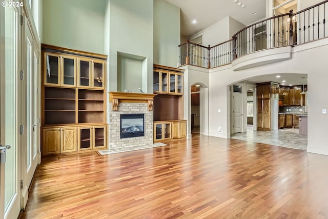 unfurnished living room featuring a fireplace, light hardwood / wood-style flooring, and a towering ceiling