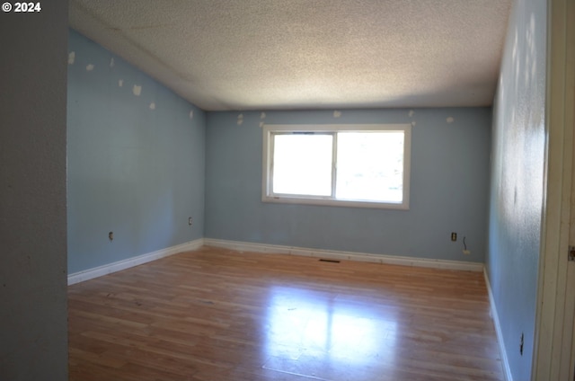 empty room with a textured ceiling and wood-type flooring